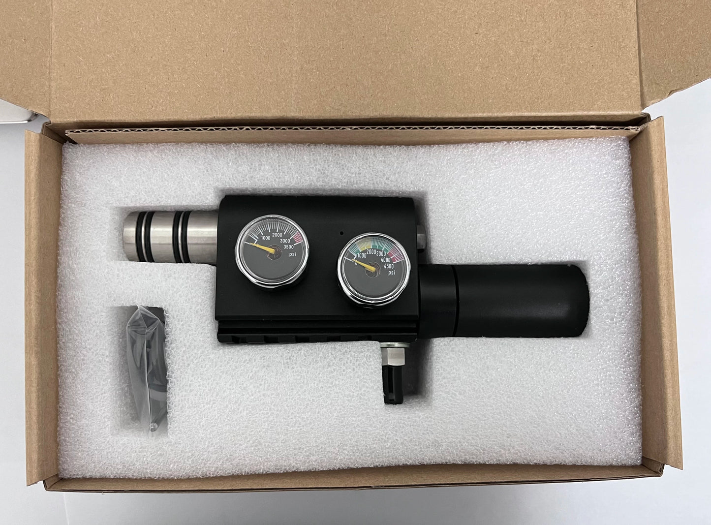 Black device with gauges in a cardboard box with white foam padding